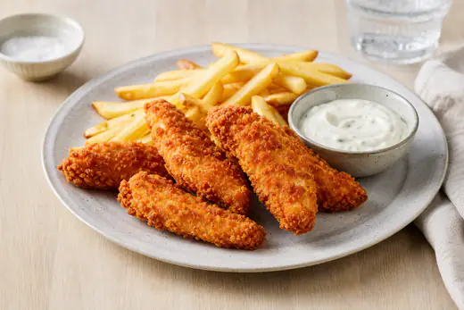 Goldbraune knusprig panierte Hähnchenstreifen auf einem Teller, dazu Pommes und ein Schälchen Dip